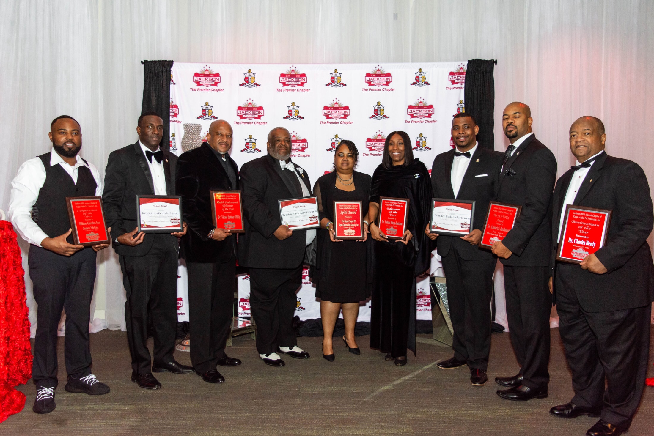 Brothers holding Vision Award plaques at Jackson Alumni chapter backdrop