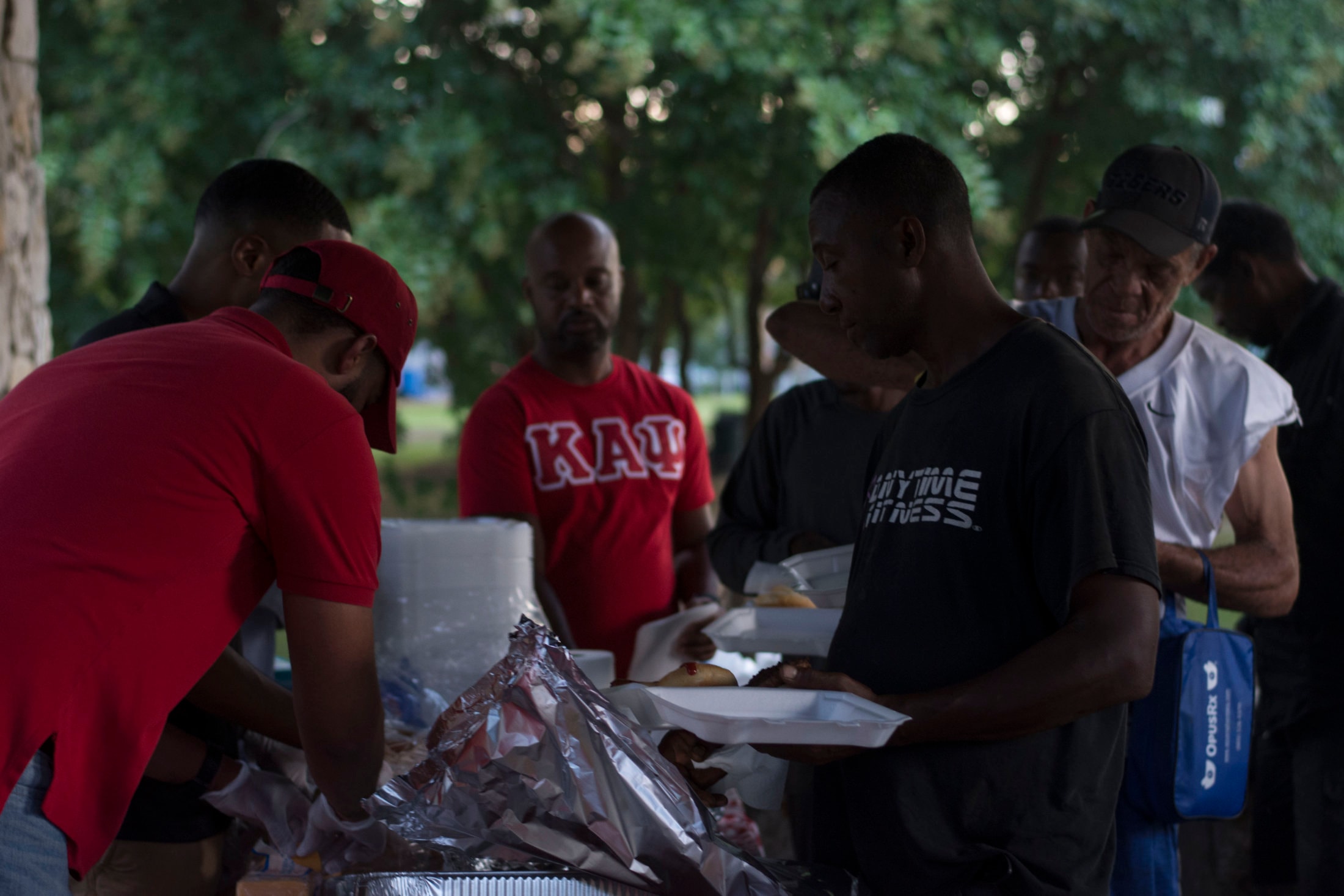 Brothers in Kappa Alpha Psi shirts serving food at outdoor community event