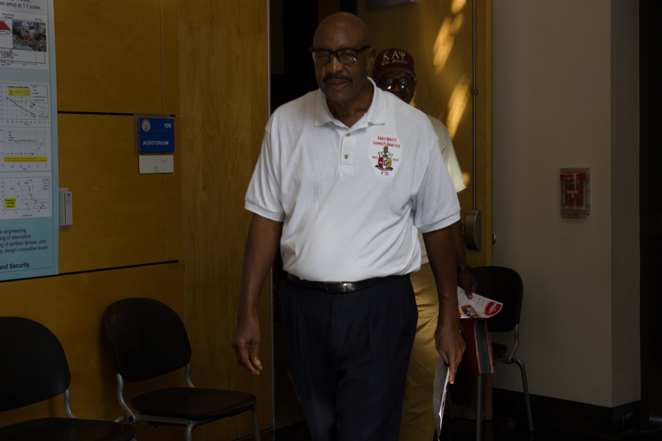 Brother in Kappa Alpha Psi polo entering auditorium for chapter meeting