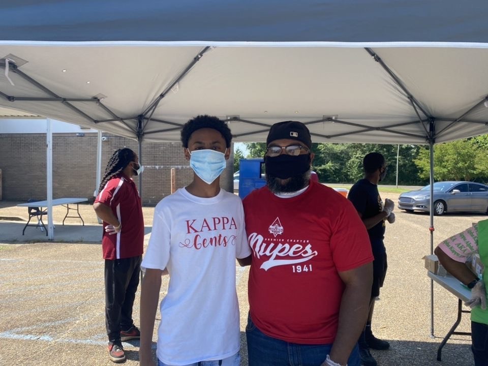 Kappa Gents youth member and brother under tent at outdoor Kappa League event