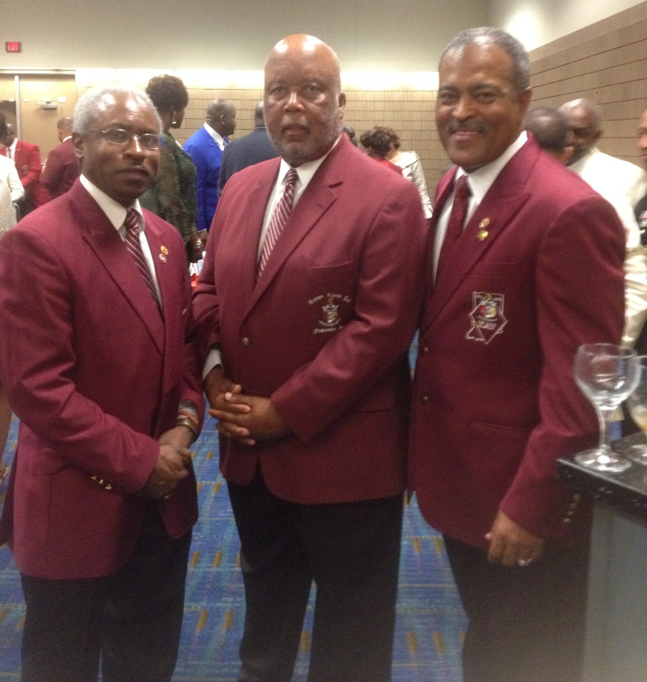 Three brothers in crimson Kappa Alpha Psi blazers at indoor fraternity event